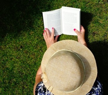 Kobieta czytająca książkę na trawie