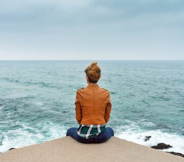 Kobieta siedząca nad brzegiem morza